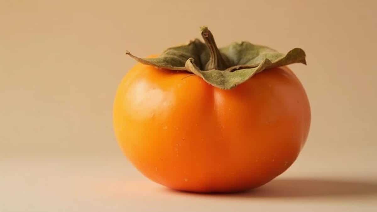 Une persimmon orange mûre et juteuse sur un fond beige.