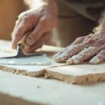 Gros plan sur les mains d'un boulanger pétrissant la pâte sur une planche en bois